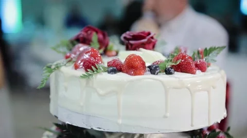 A multi-tiered white wedding cake with a floral decoration of strawberries and Stock Footage 234546681
