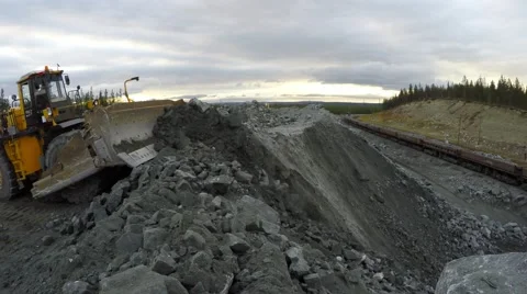 Multi-ton bulldozer works. Below are wagons with iron ore. Video stock 55857892