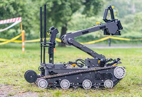 A multi-wheeled, black and silver robotic device is depicted on a grassy ar.. Stock Photos