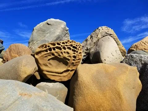 Multicavity rock in stack of boulders on beach Stock Photos
