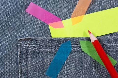 Multicolor arrow shaped postit and red pencil on jeans pocket Stock Photos
