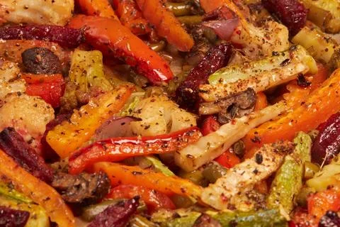 Multicolor background of sliced roasted vegetables with spices. Фото