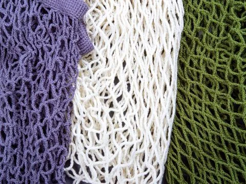The multicolor background of zero waste string bags, closeup of the knitted net. Stock Photos