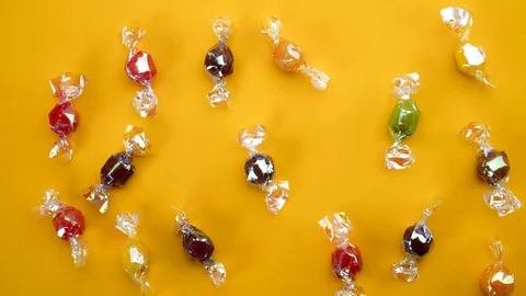 Multicolor candies on yellow background  stop motion animation 4k Stock Footage 128921240