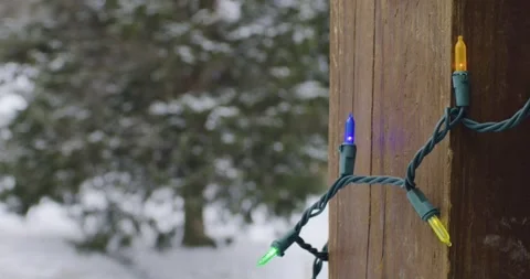 Multicolor Christmas lights on a post with tree in background Stock Footage 261591277