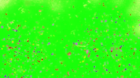 Multicolor confetti falling downwards against a bright green screen background Видео 338314553