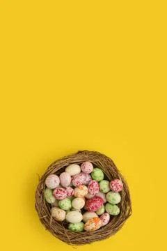 Multicolor decorated easter eggs in a nest on a yellow background. Isolated Stock Photos