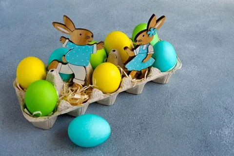 Multicolor easter eggs with easter bunnies in egg carton on grey background Stock Photos