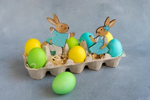 Multicolor easter eggs with easter bunnies in egg carton on grey background Stock Photos