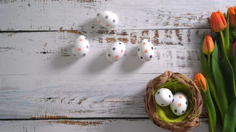 Multicolor Easter eggs rolling on white wooden table with tulips.  Stock Footage 150380243