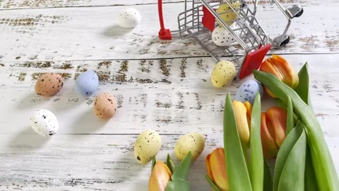 Multicolor Easter eggs rolling on white wooden table with tulips.  Stock Footage 150380335