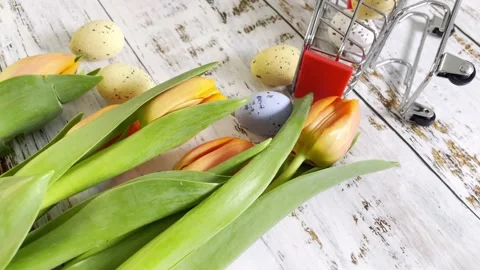 Multicolor Easter eggs rolling on white wooden table with tulips.  Stock Footage 150380550