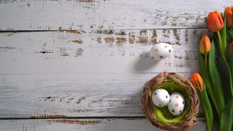 Multicolor Easter eggs rolling on white wooden table with tulips.  Stock Footage 150380732
