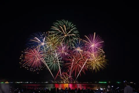 Multicolor Fireworks Display Exploding Over Reflective Night Water Landscape Stock Photos