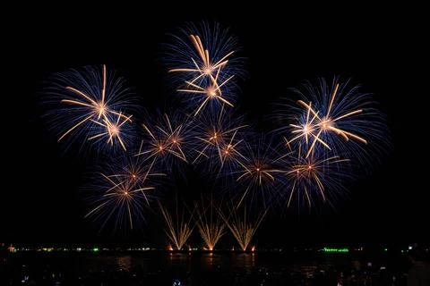Multicolor Fireworks Display Exploding Over Reflective Dark Water Wide Shot Stock Photos