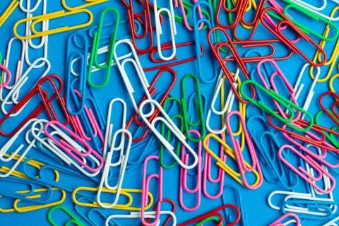 Multicolor paper clips on blue background. Back to school. Various color wire Stock Photos