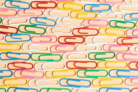 Multicolor paper clips on orange background. Back to school. Various color wi Stock Photos