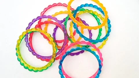 Multicolor plastic bangles rotating on white background, fashion accessory Video stock 320669346