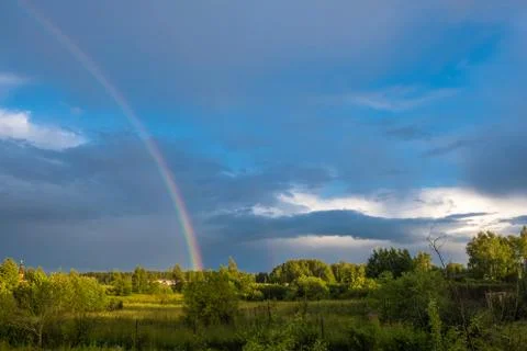 Multicolor rainbow against the dark cloudy sky, Russia. Stock Photos