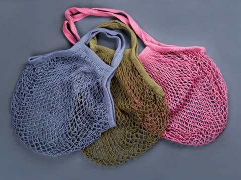 Multicolor reusable string bags for different products on the grey background. Stock Photos