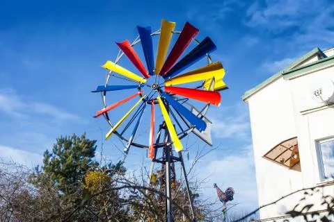 Multicolor small windmill by blue sky near house Stock-Fotos