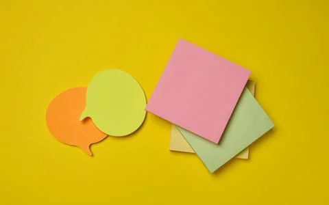 Multicolor sticky notes of various shapes and speech bubbles on a bright ye.. Stock Photos