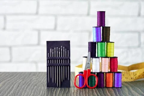 Multicolor threads bobbins placed as pyramid with scissors and needles Stock Photos
