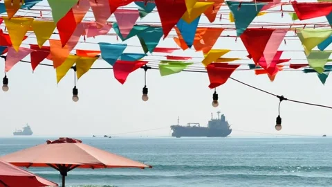 Multicolor triangular bunting flags at beach resort over calm sea with cargo Stock Footage 341544257