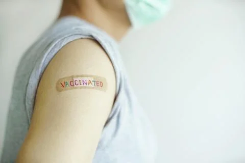 Multicolor 'VACCINATED' on plaster a man showing shoulder that received vaccine Stock Photos