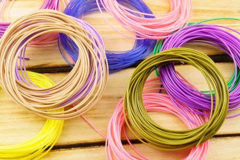 Multicolored 3D plastic for 3D pen on a wooden table. Stock Photos