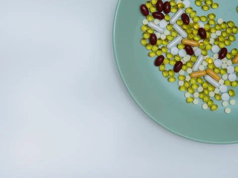 Multicolored assorted pills and vitamins on a green plate with copy space, top Stock Photos