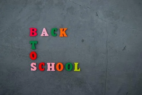 The multicolored back to school word is made of wooden letters on a grey plas Stock Photos