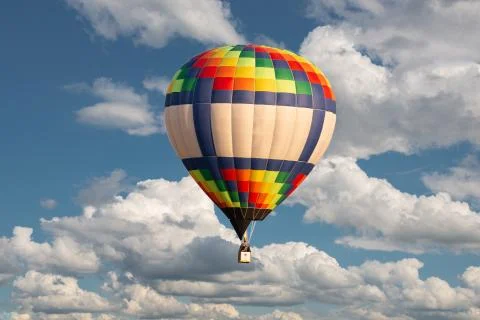 Multicolored balloon floating in the sky on the background of passing fluffy Stock Photos