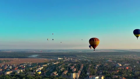 Multicolored balloons fly over fields, houses, trees. Blue sky. Stock Footage 168803203