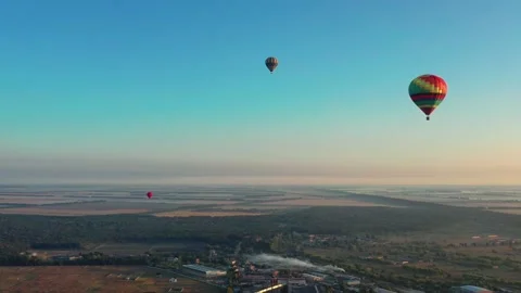 Multicolored balloons fly over fields, houses, trees. Blue sky. Video stock 170439724