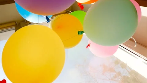 Multicolored balloons hang on the window. Slow motion. Red, blue, green Video stock 91575325