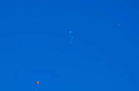 Multicolored balls, filled with helium, fly in the blue sky Foto stock