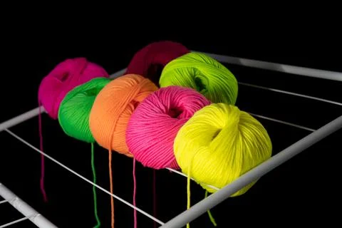 Multicolored balls of knitting threads on the clothes dryer. dark background Stock Photos