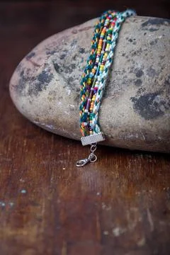 Multicolored beaded bracelet with braided threads on stone on old brown table Stock Photos