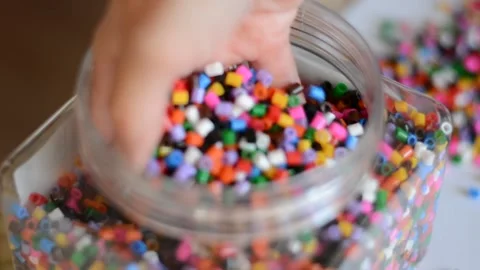 Multicolored beads in a transparent jar and female hands. Stock Footage 157045852