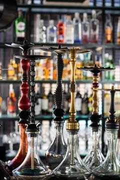 Multicolored beautiful hookahs stand on the table on the background of alcoho Stock Photos