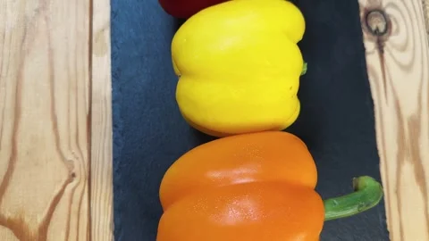 Multicolored bell peppers on flat black slate plate, top view 動画素材 337654535