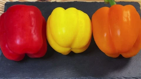 Multicolored bell peppers on a flat black slate serving plate 動画素材 337654553