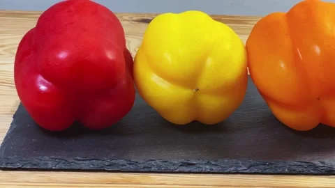 Multicolored bell peppers on flat black slate plate, side view 動画素材 337654557