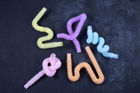 Multicolored bright tubes on black background. Anti-stress sensory figet plastic Stock Photos