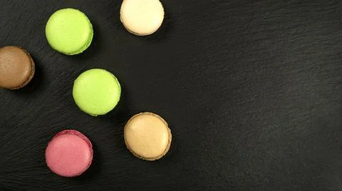 Multicolored cakes on a black background with copy space Stock Photos