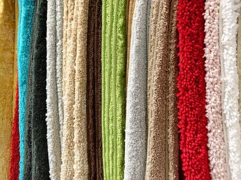 Multicolored carpets neatly displayed on a store counter for customers to b.. Stock Photos