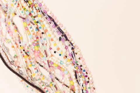 Multicolored chains of beads, pearls and natural stones on a beige background Stock Photos
