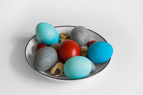 Multicolored chicken and quail colored eggs in a white plate with a black b.. Stock-Fotos