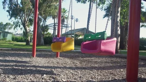 Multicolored children swing swaing by wind on empty playground in quarantine. Stock Footage 145808881